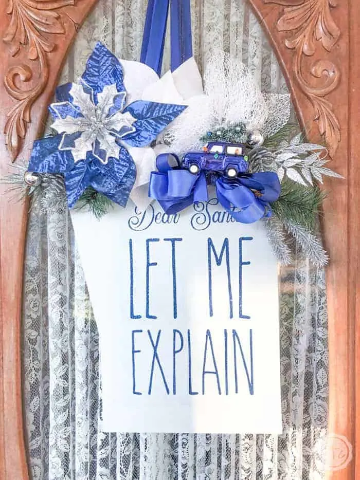 Sparkly christmas wreath that looks like a gift tag with blue flowers.