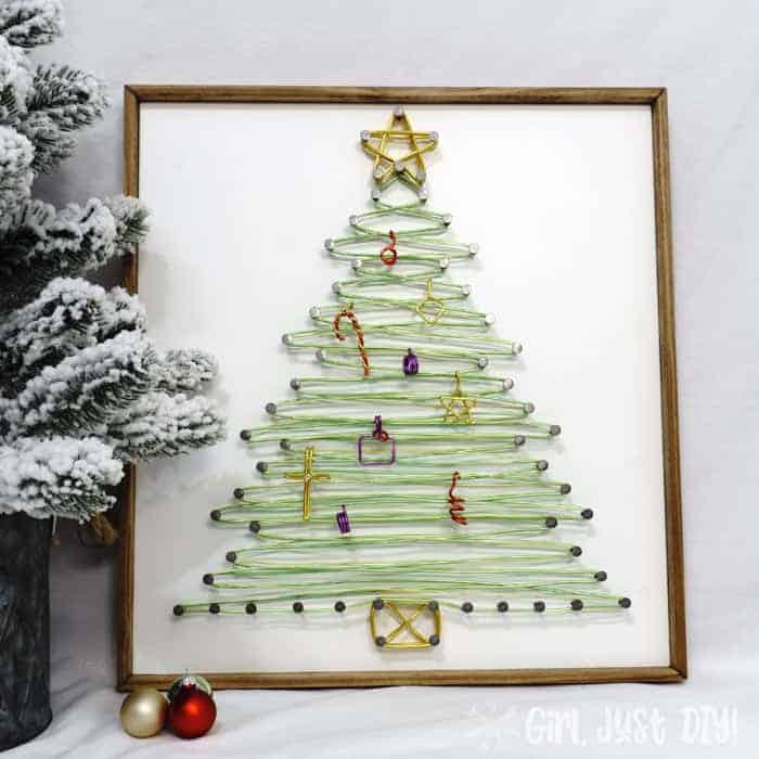 Completed String art Christmas tree on table near small faux flocked tree.