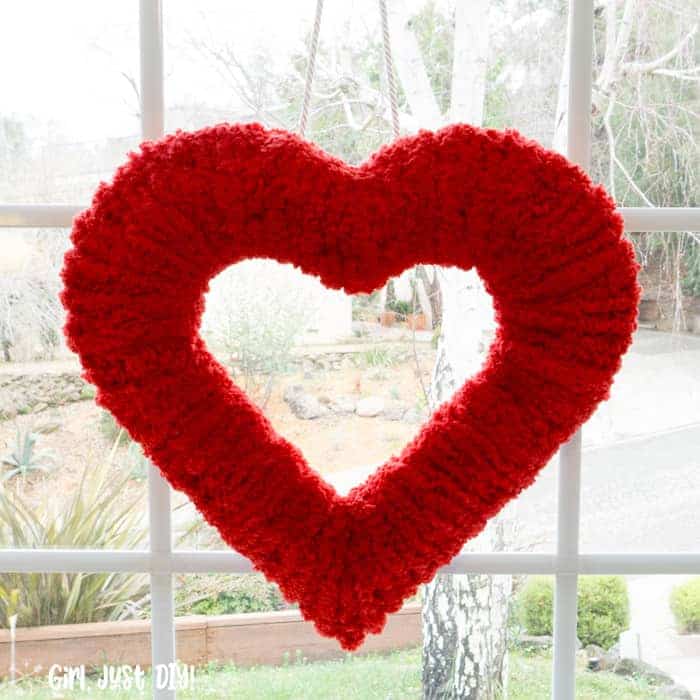 Square image of Double-sided fluffy valentine wreath hung in front window.