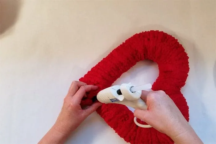 Final red fluffy yarn glued onto heart-shaped valentine wreath.