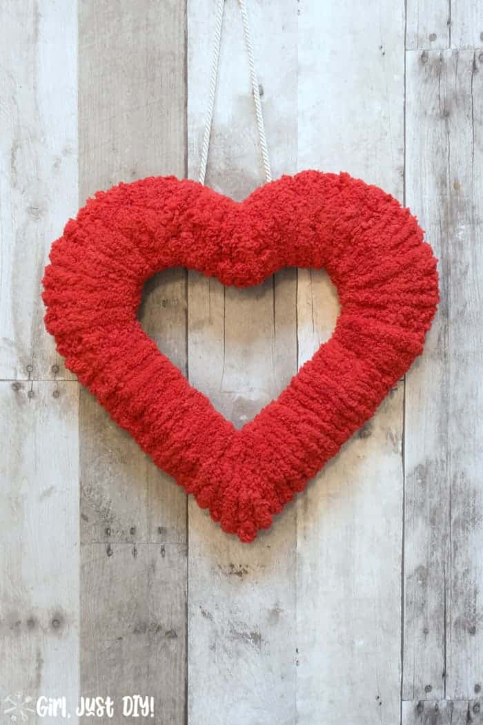 Fluffy valentine wreath hanging on wood wall.