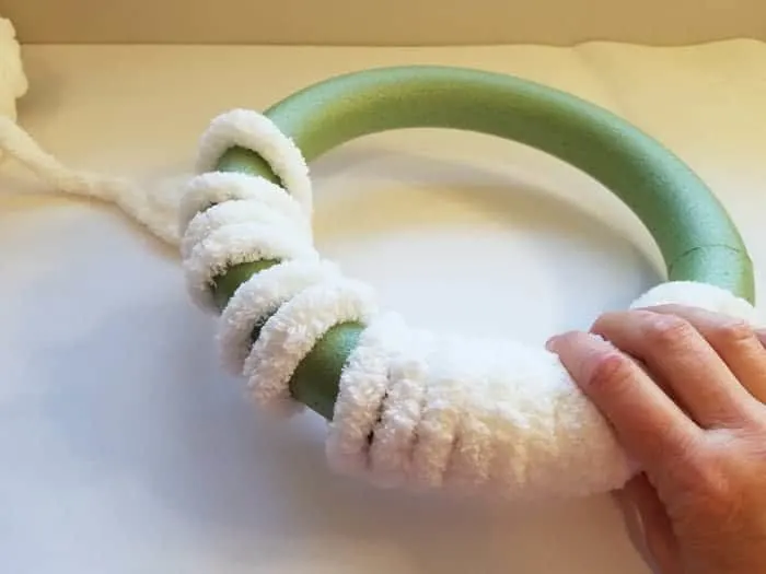 White chenille yarn wrapped halfway around a wreath form.