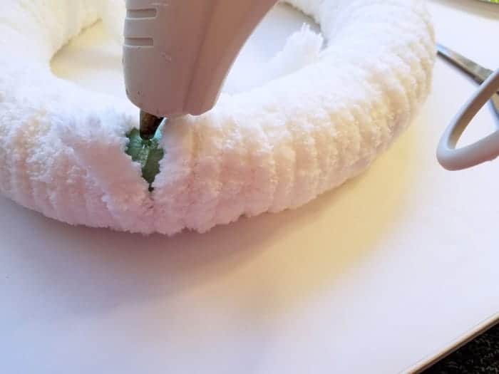 Gluing end of chenile yarn to white fluffy winter wreath.