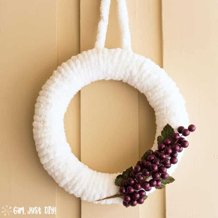 Completed white winter wreath with grape cluster hanging outside.