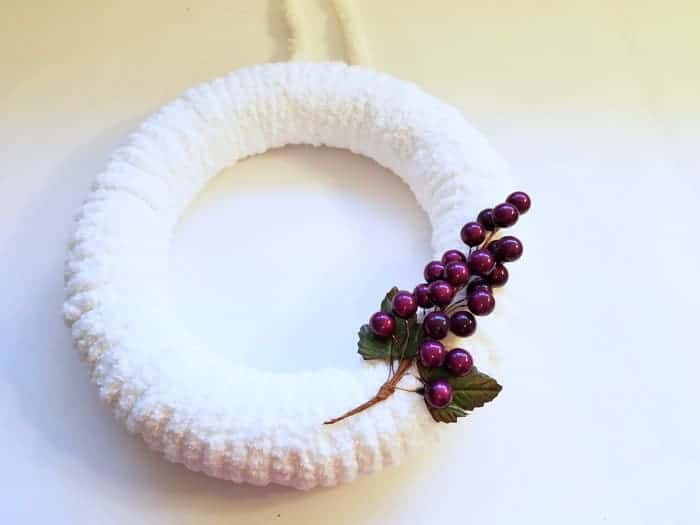 Grape cluster on front of fluffy winter wreath.