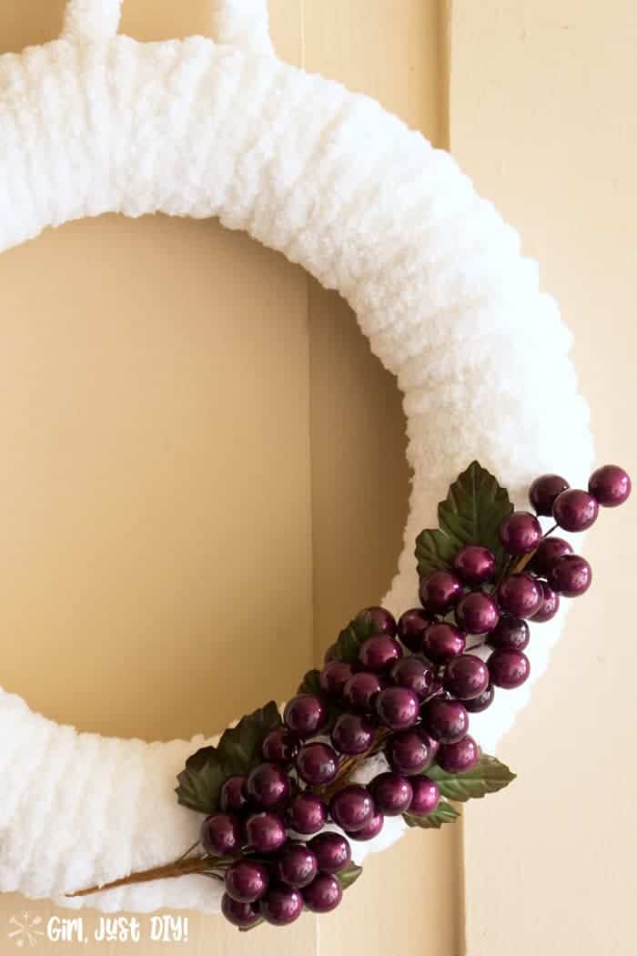 Closeup of grape clusters on white fluffy winter wreath.