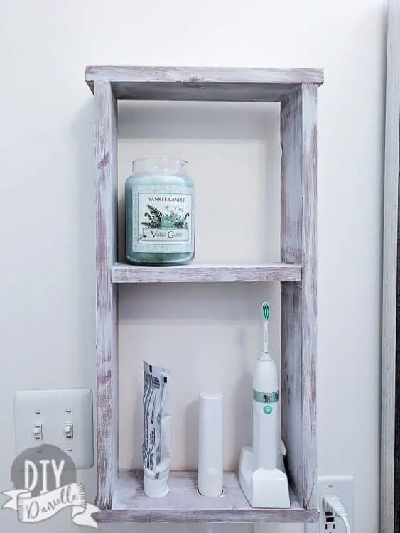 Wall shelve with electric toothbrush and supplies.