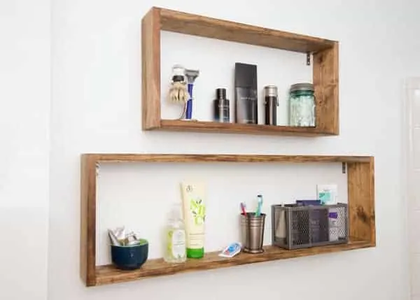 Shallow square wall shelves in bathroom with grooming supplies.
