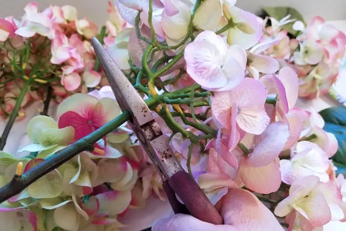Wire cutters cutting hydrangea blossom off wire stem.
