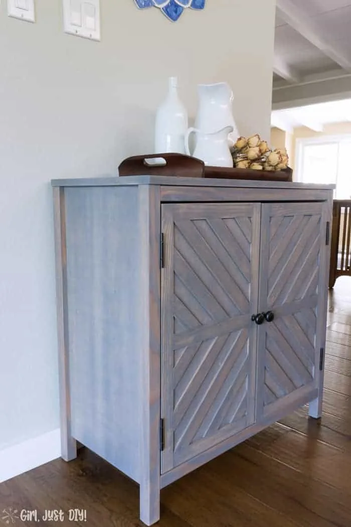 Chevron storage cabinet in dining room topped with ironstone pitchers.