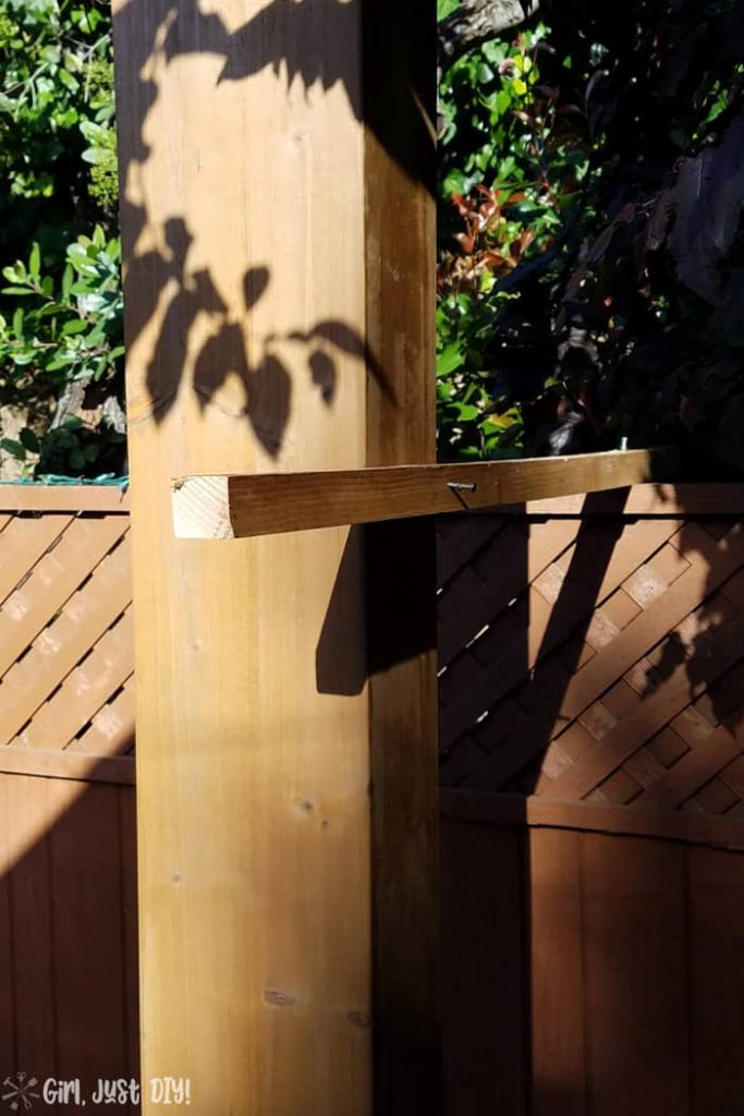 wood 2x2 attached to fence and post of diy patio gazebo.