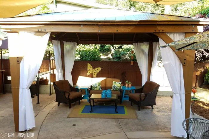 Patio furniture and curtains hung on diy patio gazebo.
