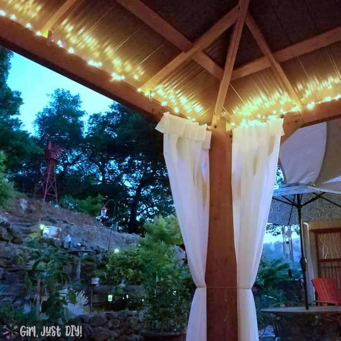 Yard view of diy patio gazebo with lights on.