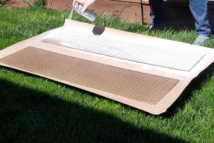 Pegboard on grass being painted white.