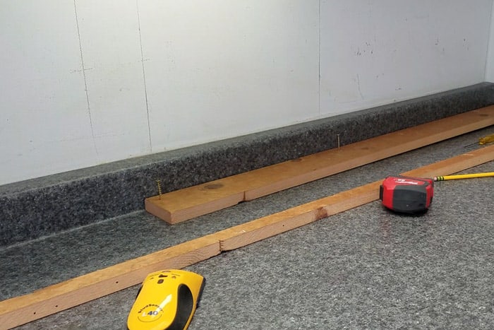 Using Stud finder to locate wood studs in wall.