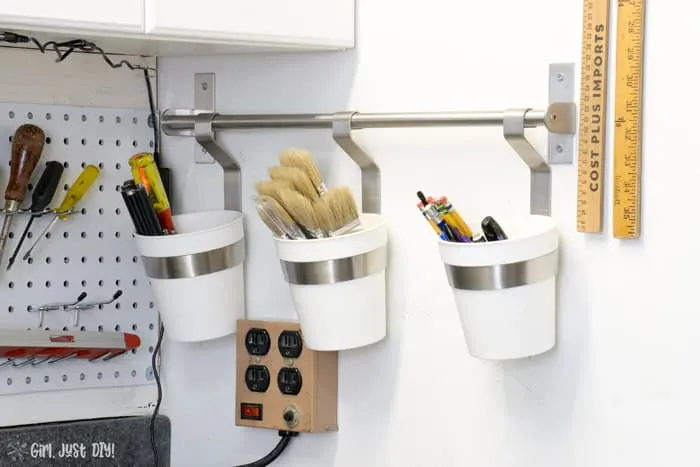 Buckets hanging on wall next to installed pegboard wall.