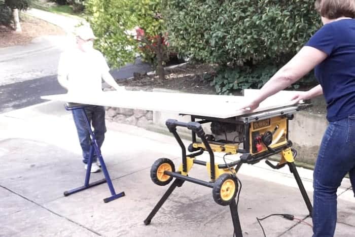 People at table saw cutting plywood to make chevron storage cabinet.