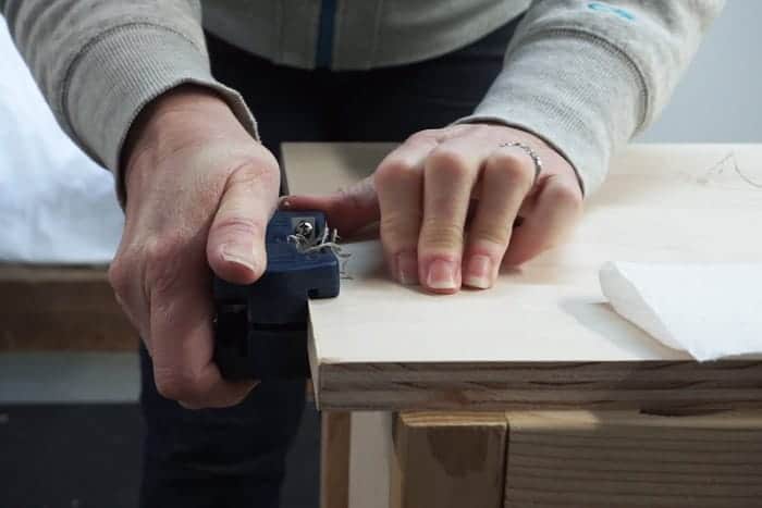 Edge trimmer cutting off edge banding from cabinet top.