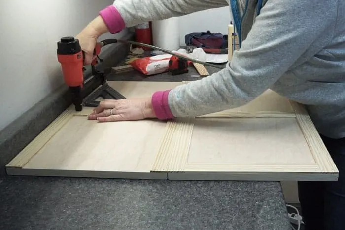 Attaching trim to doors with brad nailer.