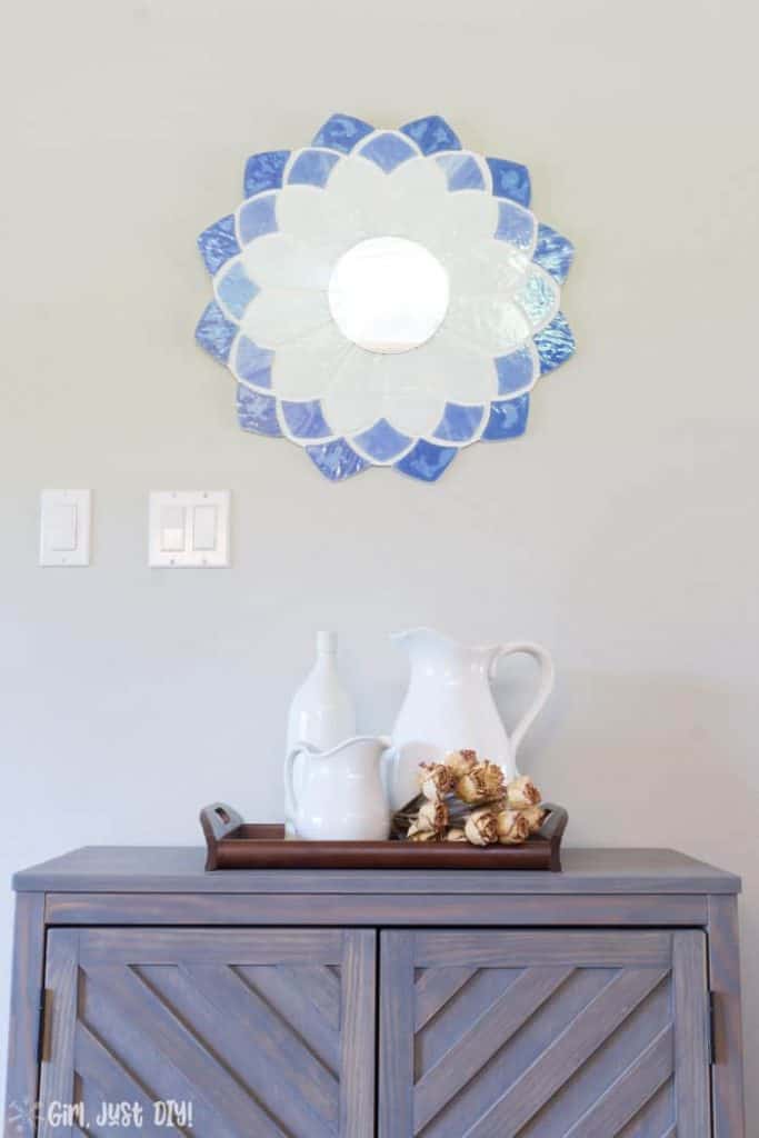 Top of chevron storage cabinet with mirror on wall above.