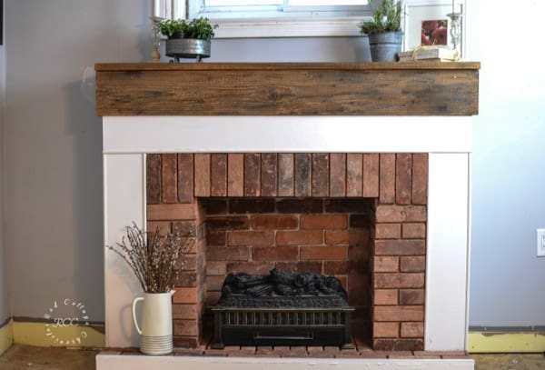 Brick fireplace with white trim and wood mantel.