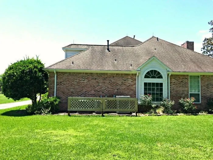 Brick house with framed wood trellis covering utility boxes.