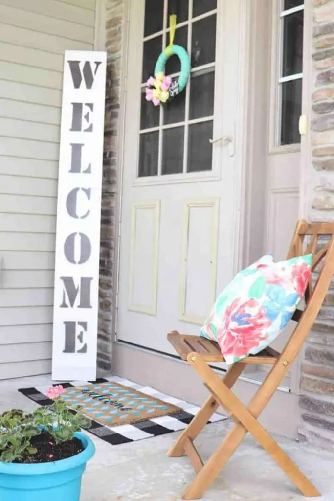 Outdoor DIY projects showing welcome sign and colorful pillow on folding wood porch chair.