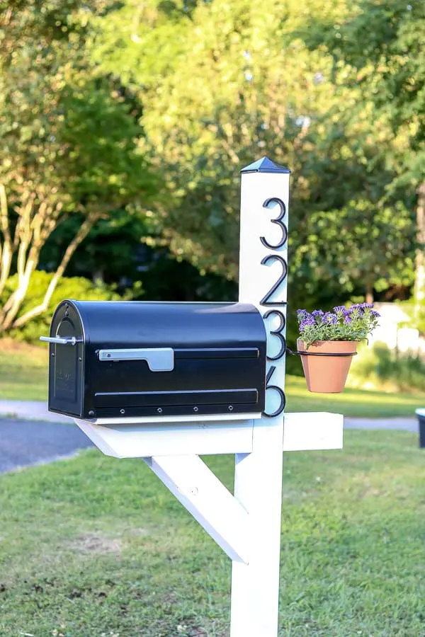 Black Mailbox on white post with address and hanging flower pot.