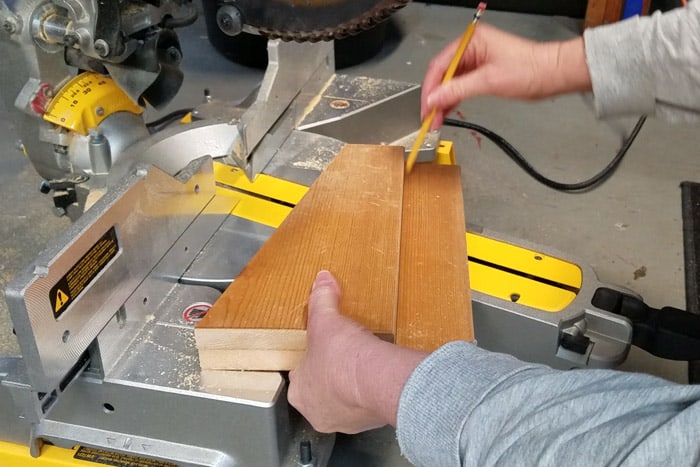 Drawing pencil line below two stacked boards.