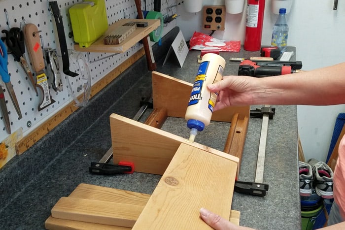 Adding wood glue to leg of footrest before attaching a top board.