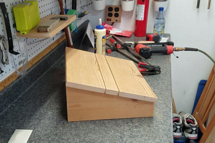 Finished diy footrest on worktable with wood glue in the background.