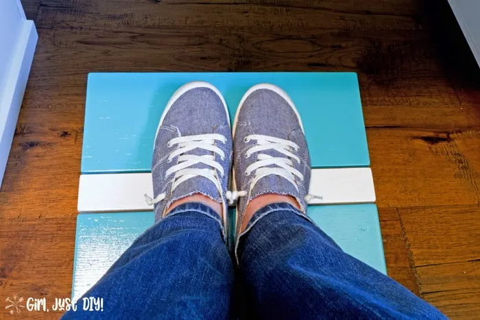 Finished diy footstool with feet inside blue tennis shoes looking down from lap.