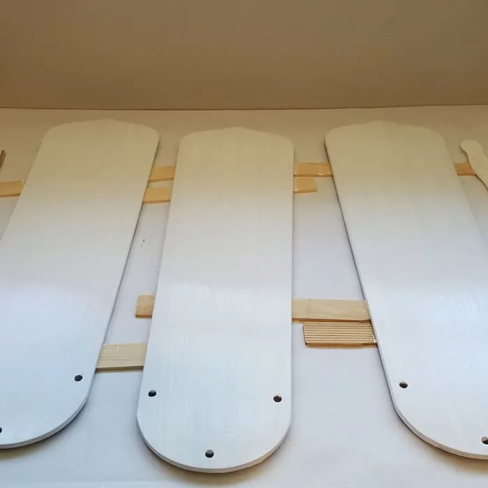 Three fan blades painted white propped on paint sticks.