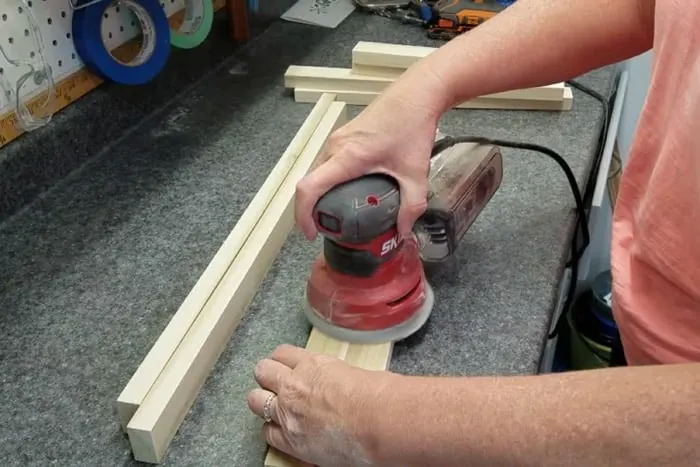 Orbital sander being used to sand diy modern end table legs smooth.