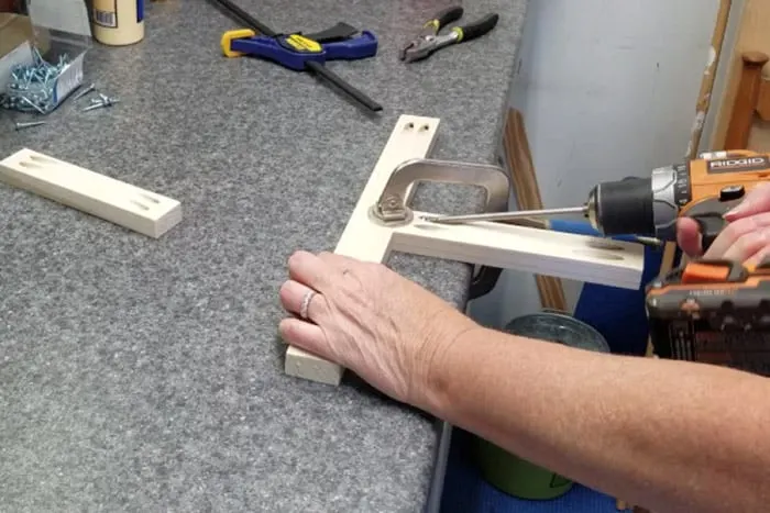 Two 1x2 boards being attached into a T with a face clamp holding them to the work table.