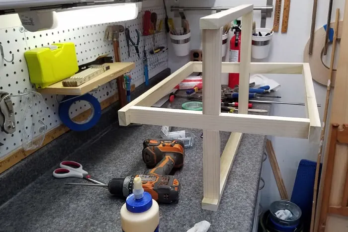 Table base laying on work bench with top and bottom braces connected to the legs.