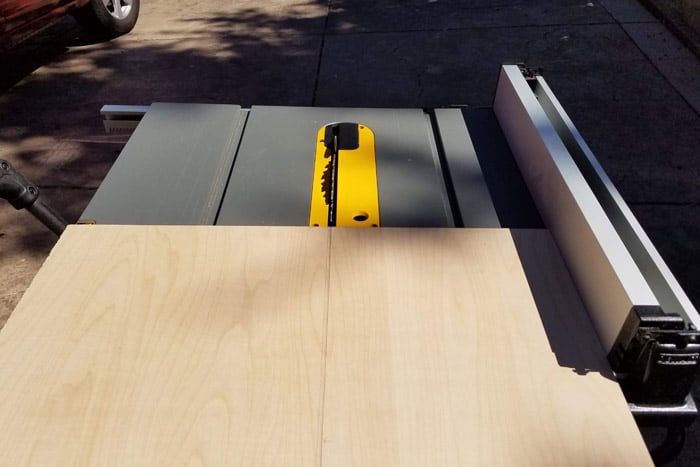 Plywood getting ripped to size on a table saw.