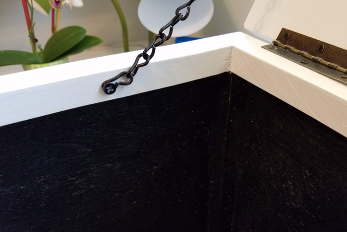 Black jack chain attached to inside of box frame and to the lid.