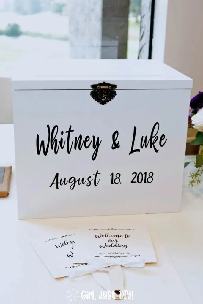 Gift table at reception showing wedding card box by a window.