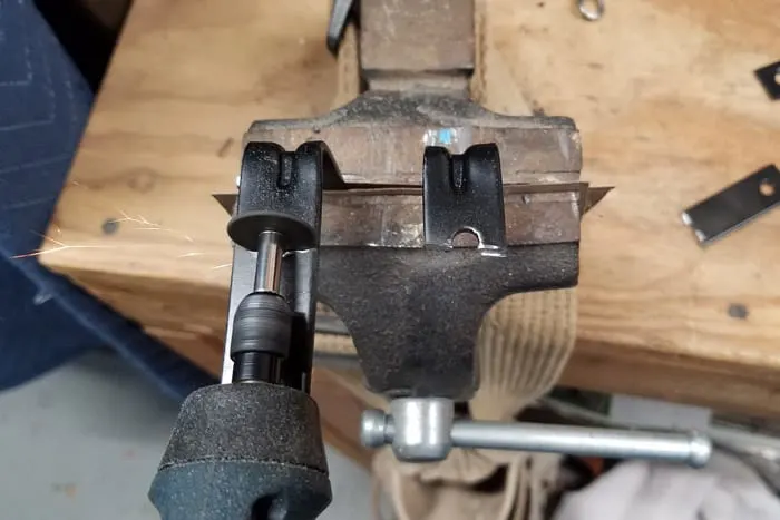 L brackets held in vice being cut with rotary tool.