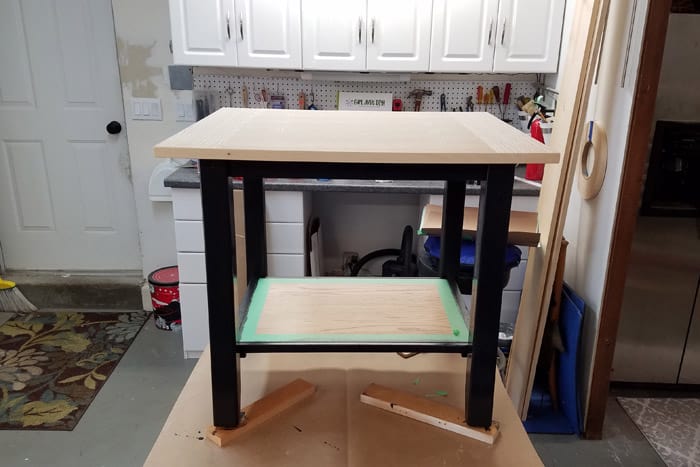 Partially painted diy industrial table on bench in garage.