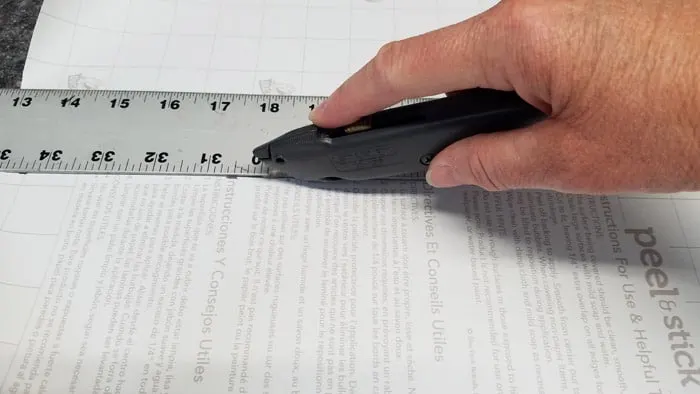utility knife cutting back of contact paper against metal ruler
