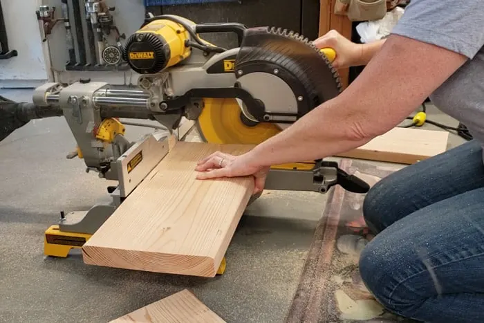 Cutting the 2x10 board on the miter saw to size for the shelves.