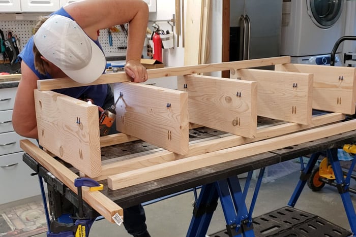 Screwing on the front legs of the plant stand from underneath.