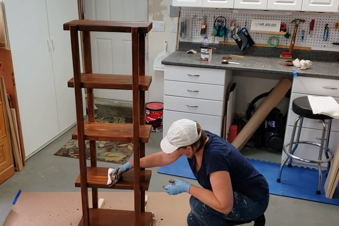 Staining the DIY 2x4 Plant Stand with brown stain.