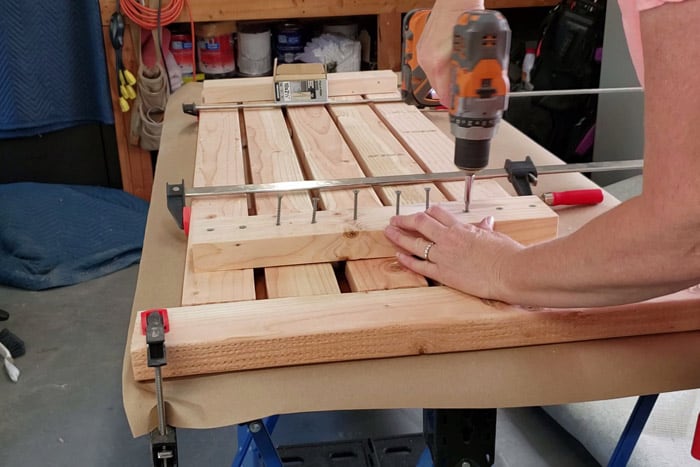 Cordless Drill and hands screwing in screws to bench top.