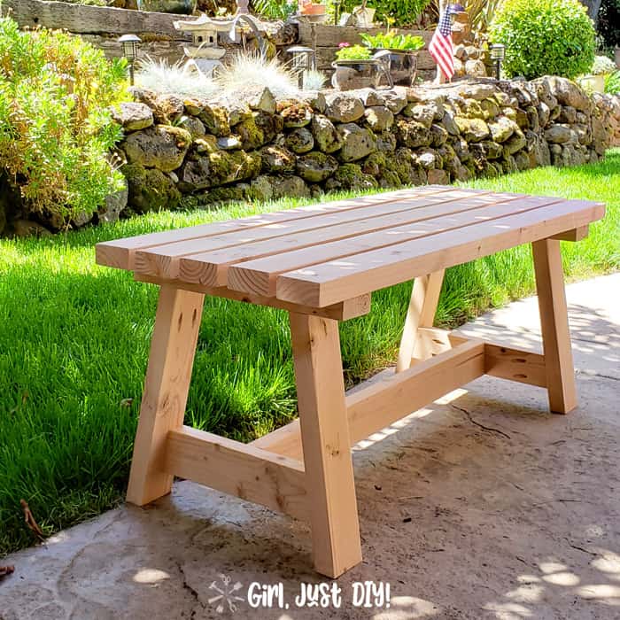 Square picture of modern 2x4 bench on patio near lawn.