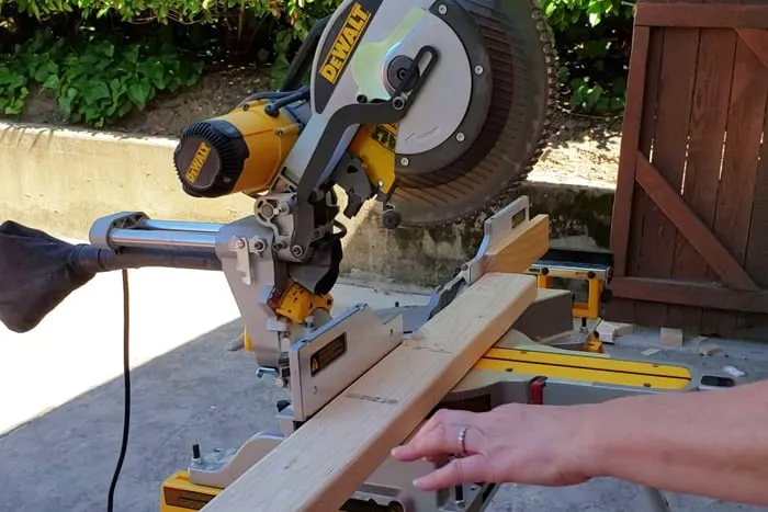 2x4 board on miter saw and being cut for giant jenga game