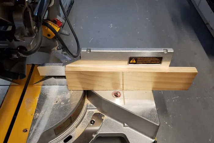 Closeup of wood added to fence as a stop piece on miter saw.