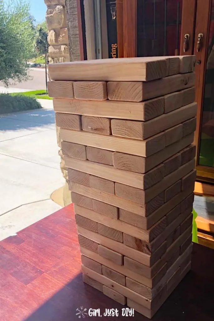 All pieces of diy giant jenga game are stacked on a table ready for play.